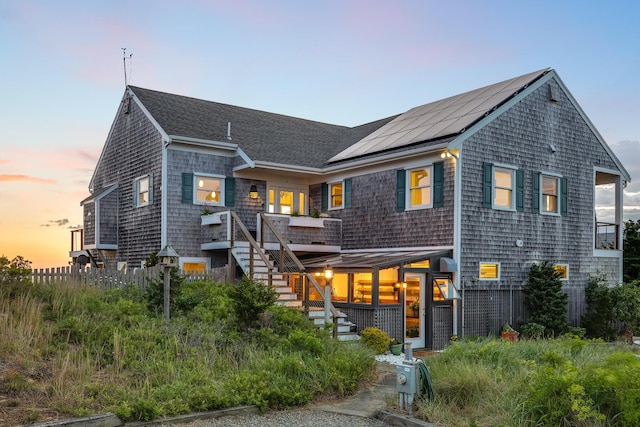 shingle-style home with stairway, solar panels, and roof with shingles