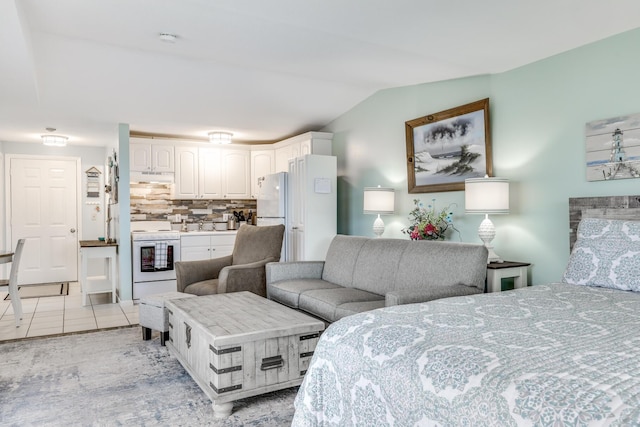 bedroom featuring vaulted ceiling, white refrigerator, and light tile patterned floors