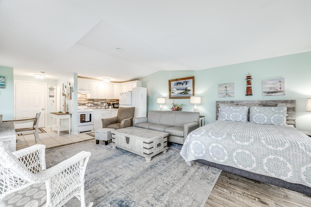 bedroom with light hardwood / wood-style floors and vaulted ceiling