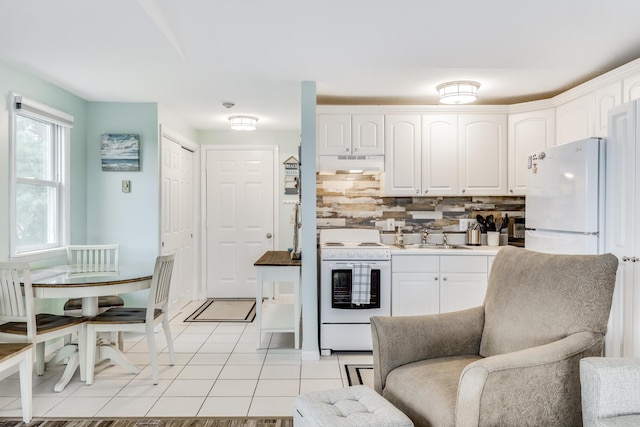 kitchen featuring white appliances, white cabinetry, sink, backsplash, and light tile patterned floors