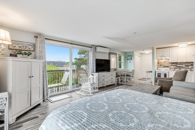 bedroom with light wood-type flooring, access to outside, and a wall unit AC