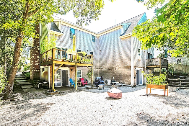 back of property featuring a fire pit, a patio, and a deck