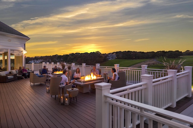 deck at dusk with an outdoor living space with a fire pit