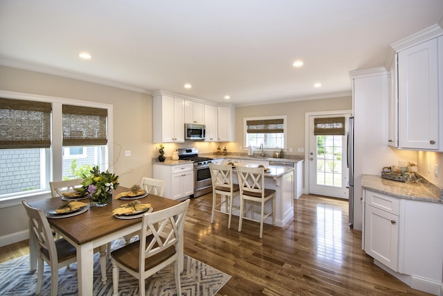 dining room with sink, a wealth of natural light, crown molding, and dark hardwood / wood-style flooring