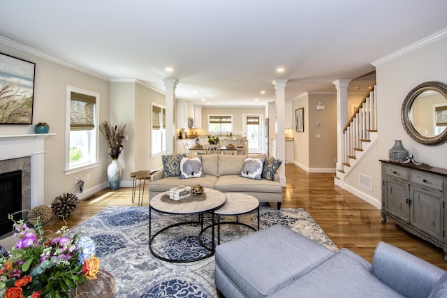 living room featuring a fireplace, decorative columns, light hardwood / wood-style flooring, and ornamental molding