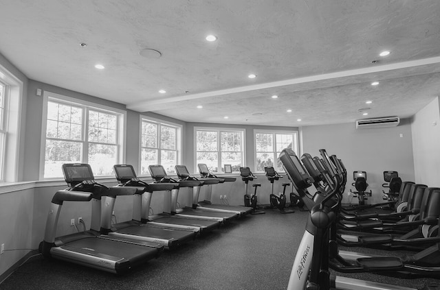 gym featuring plenty of natural light, a textured ceiling, and a wall unit AC