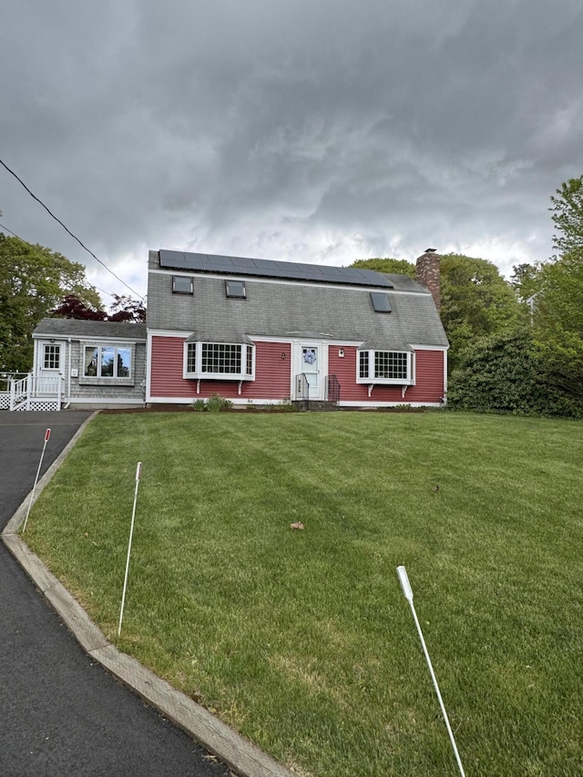 34 Charles Rd, Harwich, MA 02645 - dutch colonial with roof mounted solar panels, a chimney, a front lawn, and a shingled roof