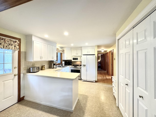 34 Charles Rd, Harwich, MA 02645 - kitchen with white appliances, a peninsula, recessed lighting, white cabinets, and light countertops