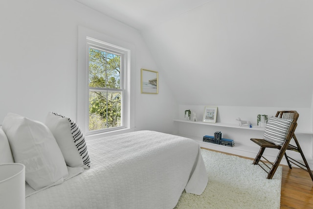 bedroom featuring wood finished floors and lofted ceiling