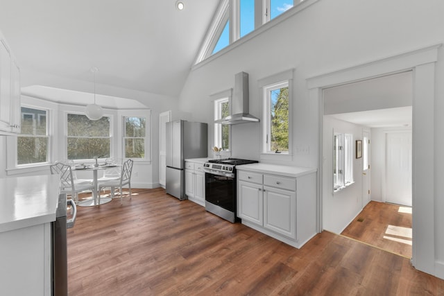kitchen featuring wall chimney exhaust hood, high vaulted ceiling, appliances with stainless steel finishes, and light countertops