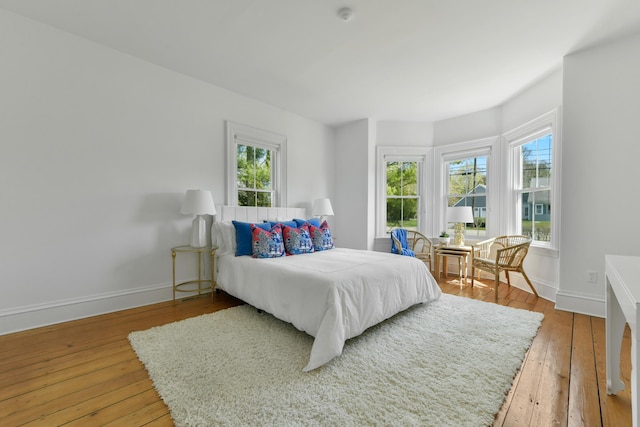 bedroom with baseboards, multiple windows, and wood-type flooring