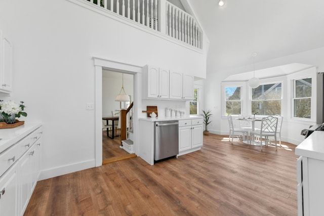 kitchen with light countertops, high vaulted ceiling, white cabinetry, baseboards, and stainless steel dishwasher