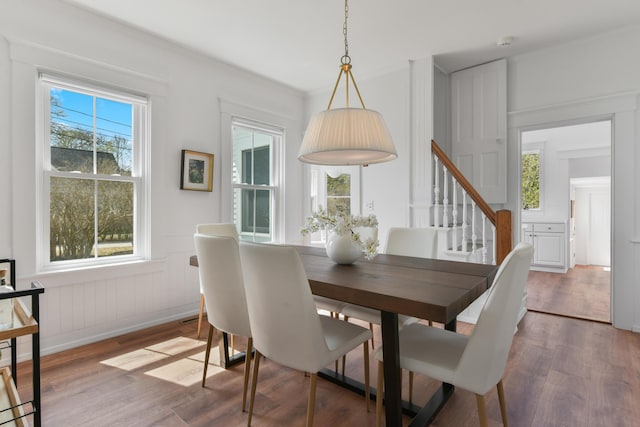 dining room featuring wood finished floors, baseboards, and stairs