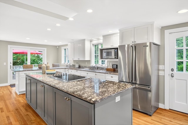 908 W Falmouth Hwy, Falmouth, MA 02540 - kitchen featuring stainless steel appliances, light wood-style floors, white cabinets, a kitchen island, and dark stone counters