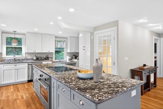 908 W Falmouth Hwy, Falmouth, MA 02540 - kitchen with stainless steel appliances, a center island, light wood finished floors, white cabinets, and dark stone countertops