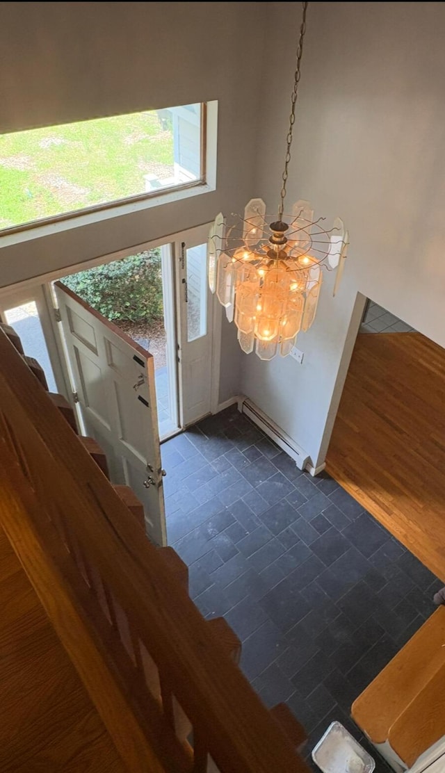 62 Musket Ln, Mashpee, MA 02649 - foyer entrance with a baseboard heating unit, a chandelier, dark tile patterned flooring, and stairs