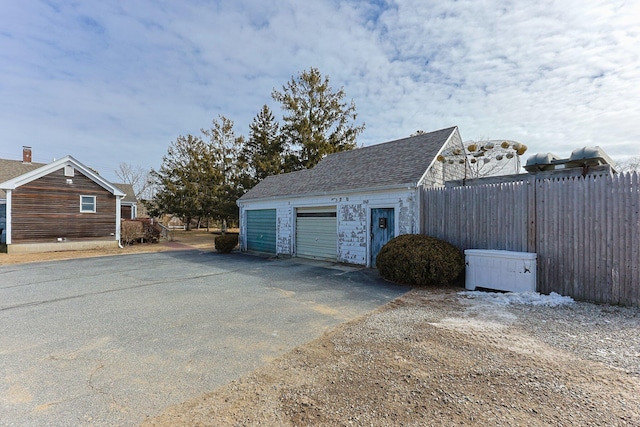 garage with aphalt driveway and fence