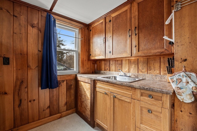 kitchen with wooden walls, light floors, a sink, and brown cabinets