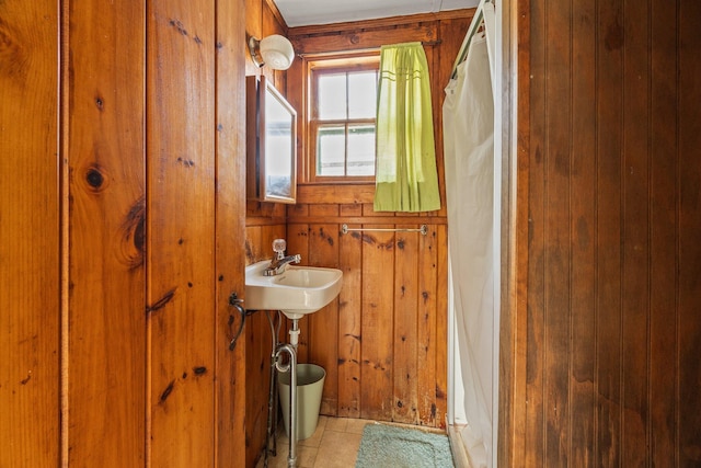 bathroom with curtained shower, tile patterned floors, and wooden walls