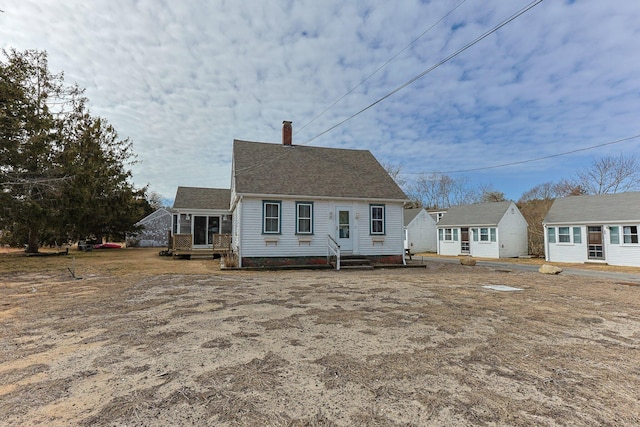 view of front of property featuring entry steps, a shingled roof, and a chimney