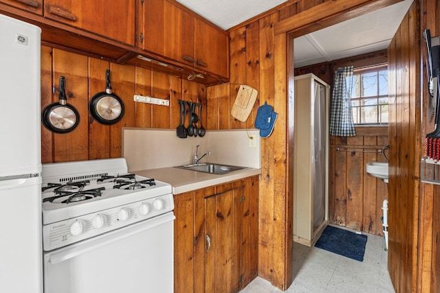 kitchen with brown cabinets, light floors, light countertops, a sink, and white appliances