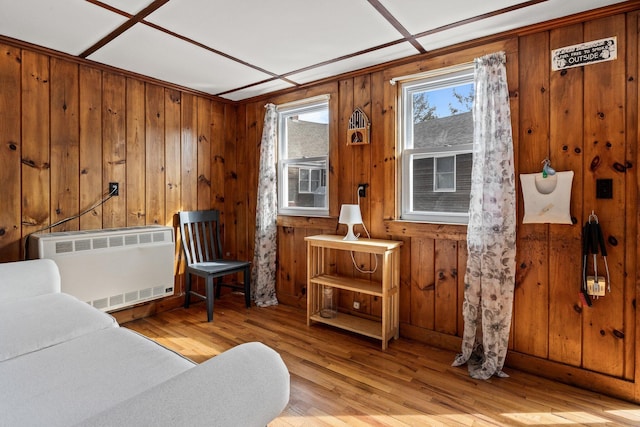 sitting room featuring radiator, wooden walls, and light wood finished floors