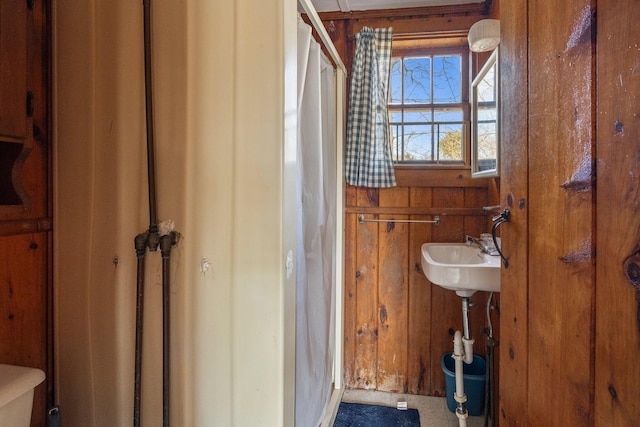 full bath with a stall shower, a sink, and wooden walls