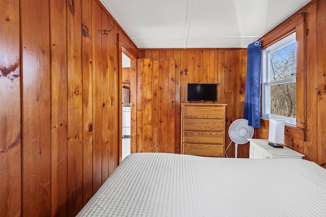 bedroom featuring washer / clothes dryer and wood walls