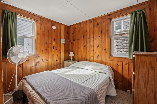 bedroom with carpet floors and wooden walls