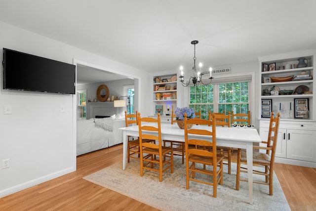 95 Red Brook Rd, Waquoit, MA 02536 - dining area featuring a chandelier, light wood-style floors, a fireplace, and plenty of natural light