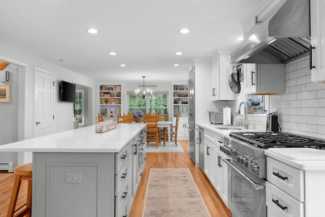 95 Red Brook Rd, Waquoit, MA 02536 - kitchen with range hood, high end appliances, a center island, a chandelier, and a breakfast bar area