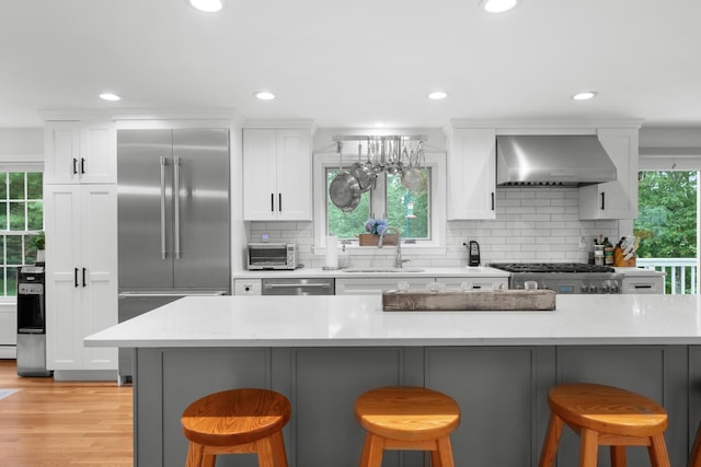95 Red Brook Rd, Waquoit, MA 02536 - kitchen featuring wall chimney exhaust hood, stainless steel appliances, white cabinetry, decorative backsplash, and recessed lighting