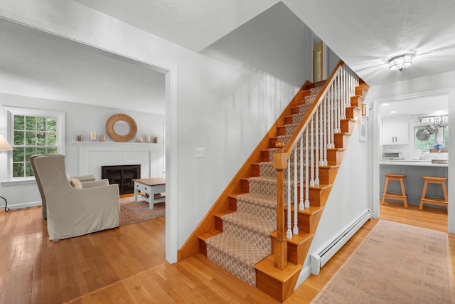 95 Red Brook Rd, Waquoit, MA 02536 - stairs featuring a baseboard heating unit, wood finished floors, and a brick fireplace