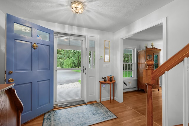 95 Red Brook Rd, Waquoit, MA 02536 - entryway featuring a textured ceiling, baseboard heating, light wood-style flooring, and stairs