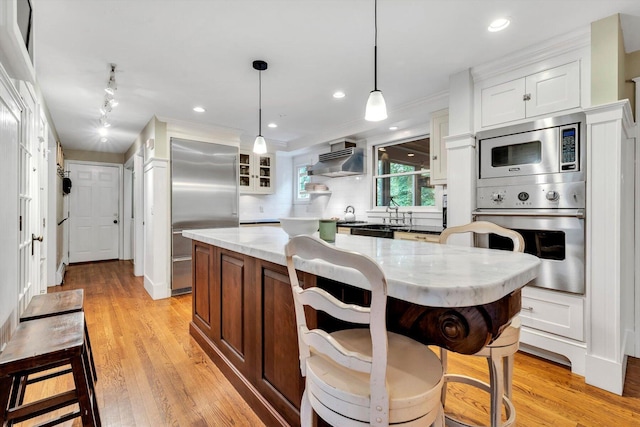 37 Tobisset St, Mashpee, MA 02649 - kitchen featuring built in appliances, decorative backsplash, white cabinetry, a kitchen island, and a kitchen bar