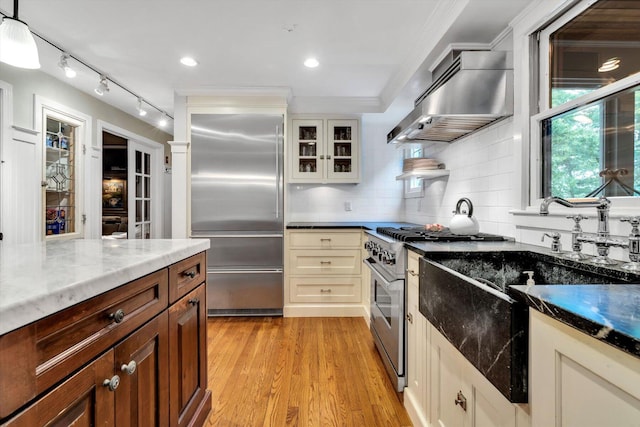 37 Tobisset St, Mashpee, MA 02649 - kitchen with exhaust hood, high end appliances, backsplash, light wood-style flooring, and glass insert cabinets