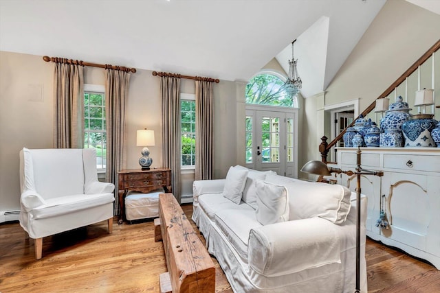37 Tobisset St, Mashpee, MA 02649 - living room with light wood-type flooring, vaulted ceiling, a baseboard radiator, stairs, and a chandelier