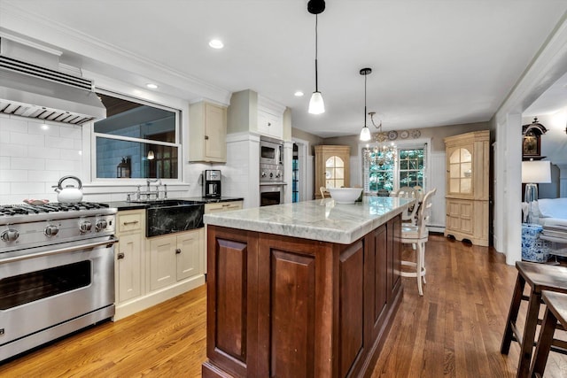 37 Tobisset St, Mashpee, MA 02649 - kitchen with appliances with stainless steel finishes, extractor fan, a kitchen island, backsplash, and light wood-style flooring