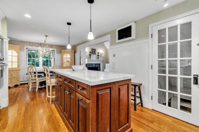 37 Tobisset St, Mashpee, MA 02649 - kitchen featuring light wood-type flooring, brown cabinets, light countertops, pendant lighting, and a decorative wall
