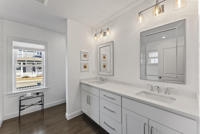 full bathroom featuring double vanity, baseboards, a sink, and wood finished floors