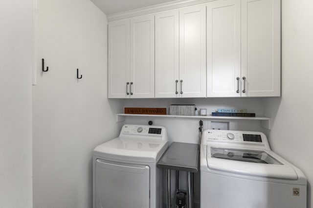 clothes washing area with washing machine and dryer and cabinet space