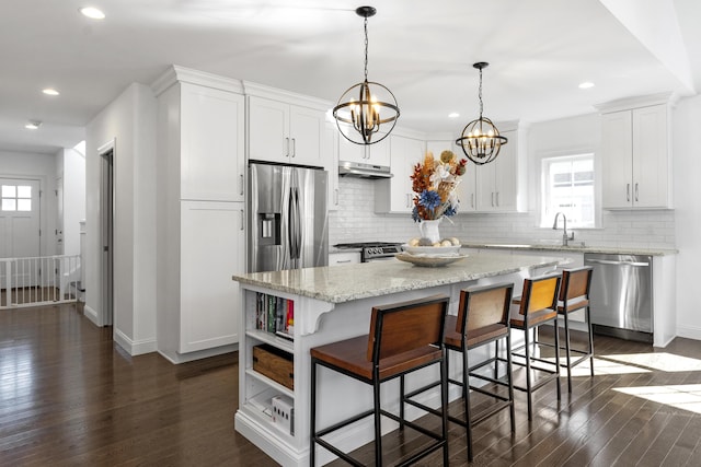 kitchen featuring appliances with stainless steel finishes, dark wood finished floors, under cabinet range hood, and a kitchen island