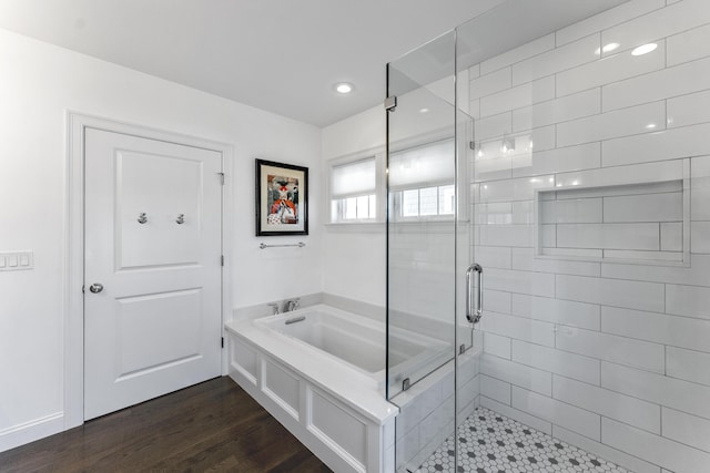 bathroom featuring a bath, a stall shower, and wood finished floors