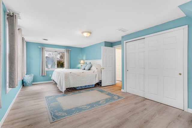 bedroom with visible vents, baseboards, wood finished floors, and a closet