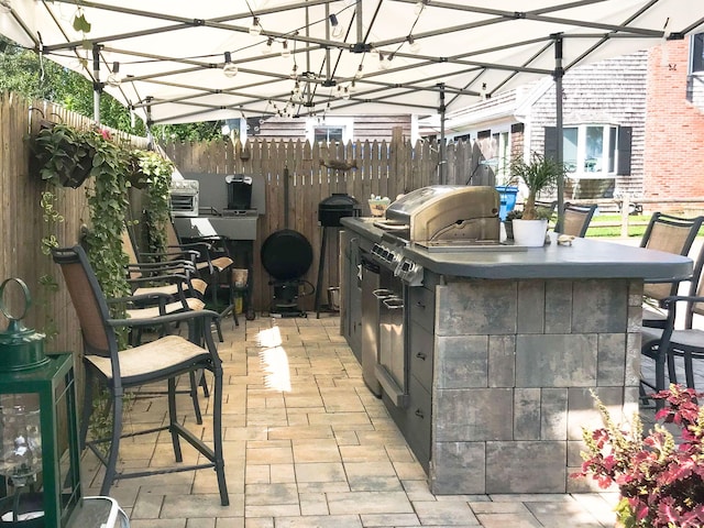 view of patio / terrace featuring fence, outdoor dry bar, and exterior kitchen