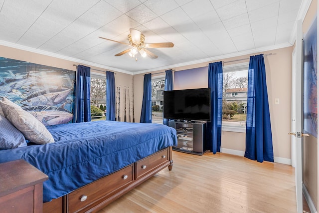 bedroom featuring crown molding, baseboards, ceiling fan, and light wood-type flooring