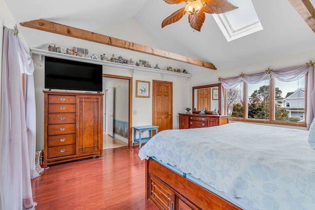bedroom with a ceiling fan, light wood finished floors, and lofted ceiling with skylight