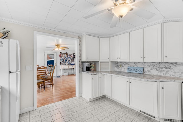 kitchen featuring ceiling fan, freestanding refrigerator, and white cabinets