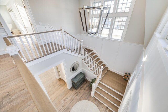 staircase with wood-type flooring, a towering ceiling, and an inviting chandelier