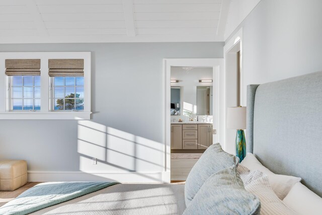 bedroom with ensuite bathroom, beam ceiling, light hardwood / wood-style floors, and wooden ceiling